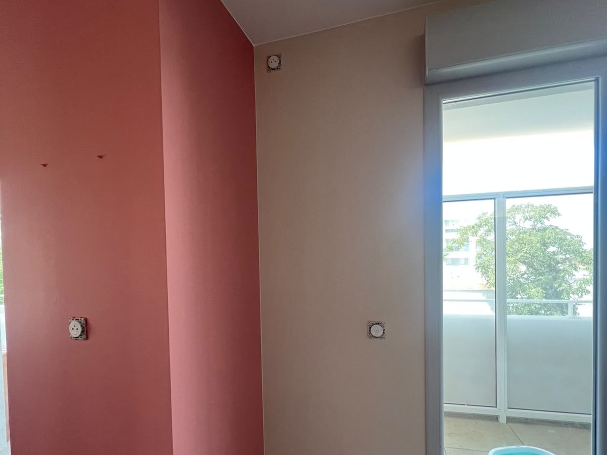 Un mur peint en rouge à côté de la porte-fenêtre